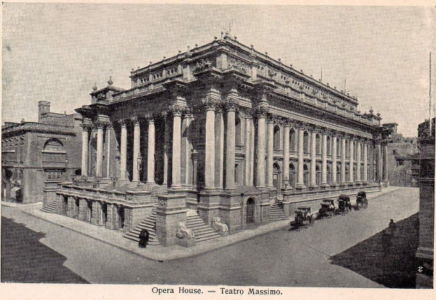 Ein altes Schwarzweißfoto des Teatro Massimo Opernhauses in Rom, Italien, das ein großes Gebäude mit Säulen, Stufen und Bögen zeigt, sowie einige Menschen und Karren auf der Straße davor und Text am unteren Rand des Bildes.