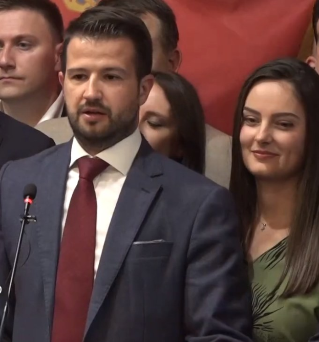 Ein Mann im Anzug spricht an einem Rednerpult mit einem Mikrofon zu einer Menge hinter einem Banner, wahrscheinlich als Reaktion auf ein Regierungsverbot von Social Media.