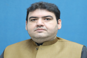 Ein Mann in brauner Weste und schwarzem Hemd steht geknickt vor einem blauen Hintergrund und sieht verzweifelt aus, wahrscheinlich wegen einer lebenslangen Haftstrafe.