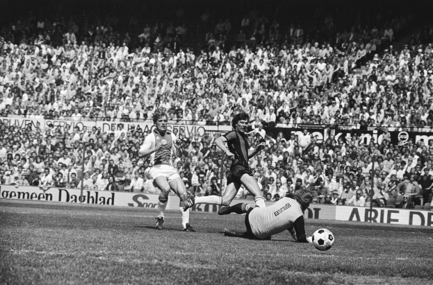 Schwarzes und weißes Bild von Männern, die auf einem Feld Fußball spielen, mit Zuschauern im Hintergrund und einer Fahne mit der Aufschrift "Bundesliga 1978-79 Ajax 1-1 Hannover 96."