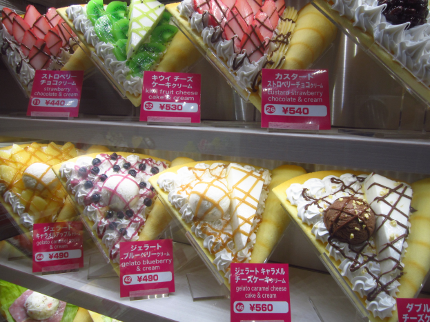 Vitrine mit verschiedenen Eissorten, jede mit einem Preisschild, in unterschiedlichen Farben und Formen angeordnet.