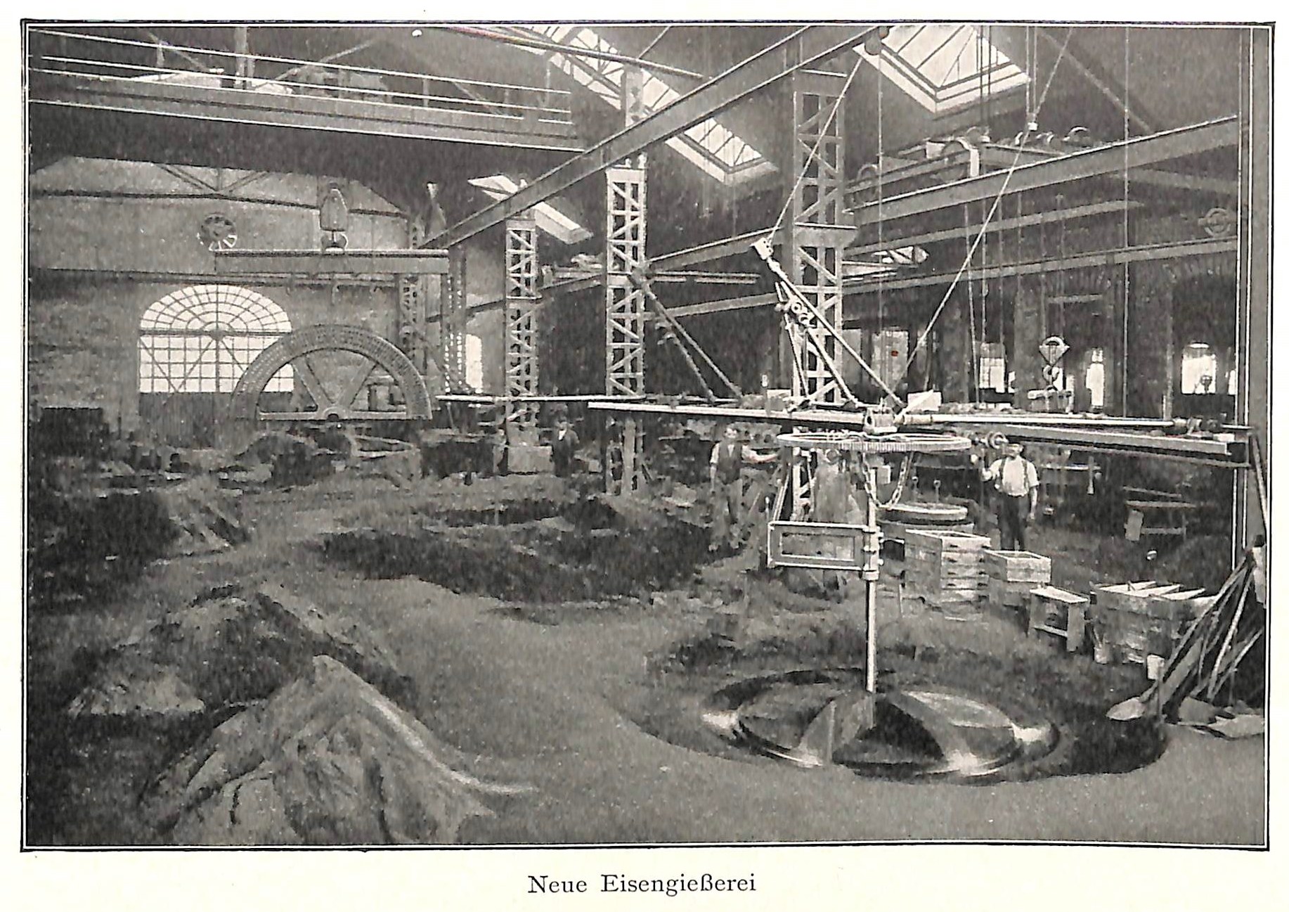 Schwarze und weiße Fotografie eines Werks mit Arbeitern, die Maschinen bedienen, umgeben von Metallstangen und -pfählen, beschriftet mit "Neue Eisenglebeerei, die erste Fabrik in Deutschland" unten.