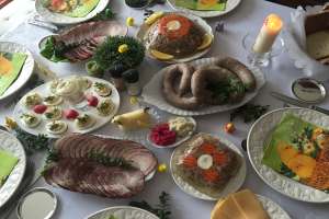 Ein lang gedeckter Tisch mit verschiedenen Speisen, Besteck, Gläsern, Kerzen und Stühlen, der eine traditionelle deutsche Oster-Mahlzeit vermuten lässt.