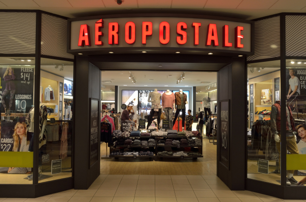 Aeropostale-Laden im Einkaufszentrum mit Schaufensterpuppen, Kleiderständern, Schildern, Glaswänden und Beleuchtung, die auf eine Schließung im Juni hinweist.