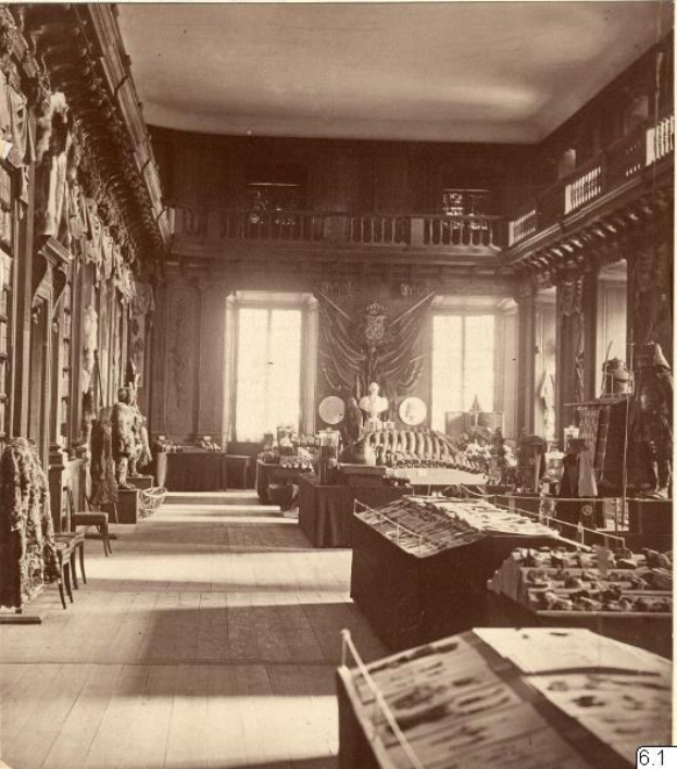 Schwarzes und weißes Foto eines Museumsraums mit Tischen, Stühlen, Skulpturen an den Wänden, Fenstern mit Vorhängen und Geländern, beschriftet mit "The Museum of Fine Arts, London" unten.