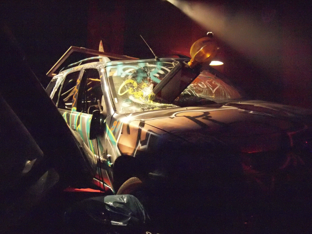 Ein geschädertes Auto mit sichtbarem Rad und Reifen an der Seite einer dunklen Straße.