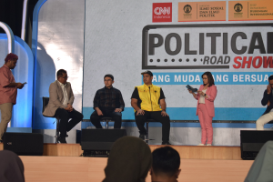 Eine Gruppe von Menschen auf einer Bühne mit einigen vorne an einem Podium und ein Schild im Hintergrund mit der Aufschrift "Cnn Political Road Show".