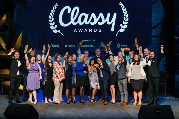 Gruppe von Menschen auf einer Bühne mit Auszeichnungen, 'Classy Awards 2019' auf einem Bildschirm im Hintergrund.