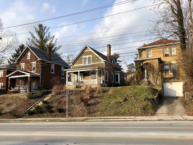 Reihe von Häusern entlang einer Straße mit Fenstern, Türen, Geländern und Stufen, vor einem bewölkten Himmel, repräsentiert eines der teuersten Häuser zum Verkauf in Detroit.