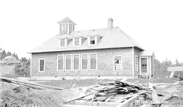 Schwarz-weiß-Foto eines Regierungsgebäudes aus dem Jahr 1905, umgeben von Bäumen unter einem klaren Himmel, mit Holzplanken und dem Text "Regierungsgebäude, Thwaites, 1905" unten.