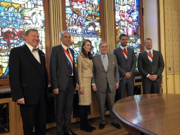 Gruppe von Menschen, wahrscheinlich Mitglieder der Königsfamilie, die vor einem Buntglasfenster stehen, mit einem Tisch im Vordergrund und einer Wand im Hintergrund.