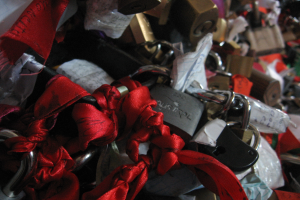 Eine Sammlung von Vorhängeschlössern mit roten Bändern, die in Schleifen gebunden sind, jedes mit kursiver Schrift, ordentlich in Reihen angeordnet.