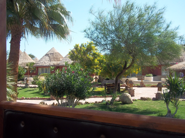 Ein Resort-Blick mit Hütten, Grün, Felsen, einer Bank und Himmel.