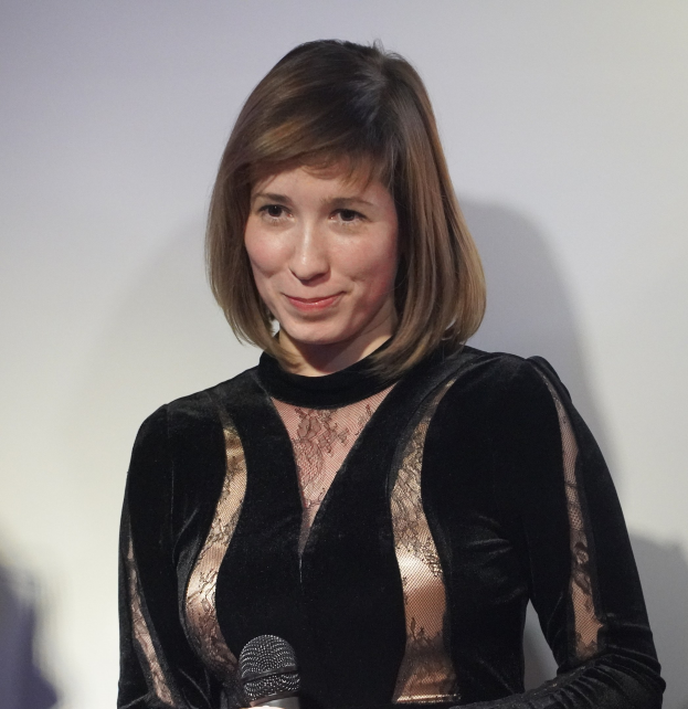 Frau in schwarzem Kleid mit Mikrofon während eines BBC Radio 1-Interviews vor einer Wand.