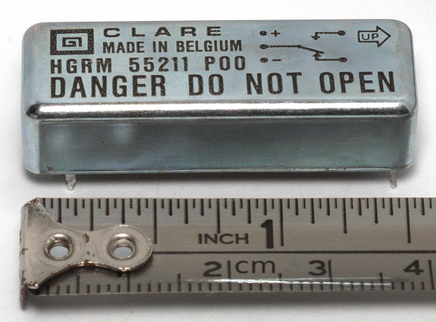 Metallbox mit der Aufschrift "Danger Do Not Open" neben einem Lineal auf einer weißen Oberfläche