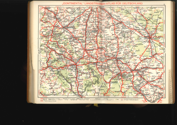 Ein aufgeschlagenes Buch mit einer detaillierten Deutschlandkarte, die Straßen und Autobahnen zeigt, vor schwarzem Hintergrund.