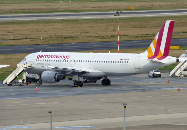 Germanwings Airbus A320-200 auf dem Frankfurter Flughafen mit Bodenfahrzeugen, Verkehrskegeln, Pfosten und Gras im Hintergrund.